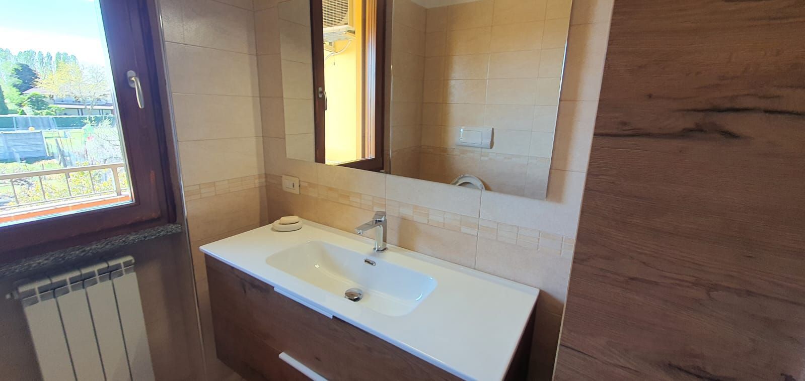 Un bagno con lavandino, specchio e finestra.