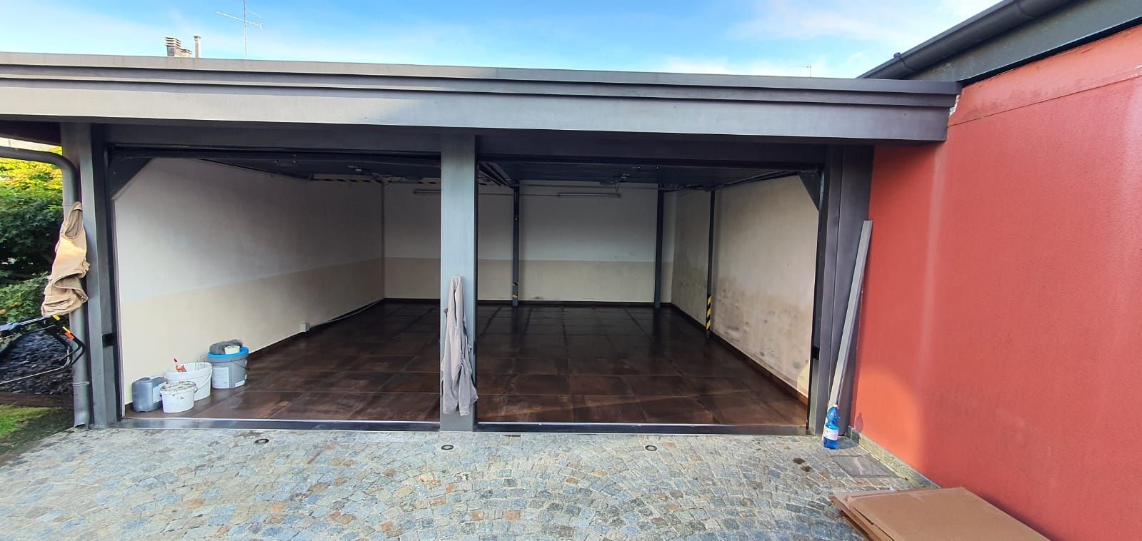 Un garage vuoto con un muro rosso e un tetto.