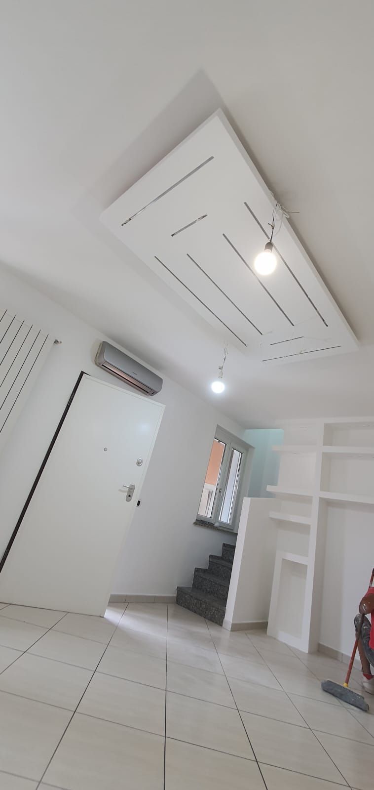 Una stanza con un ventilatore a soffitto e delle scale.