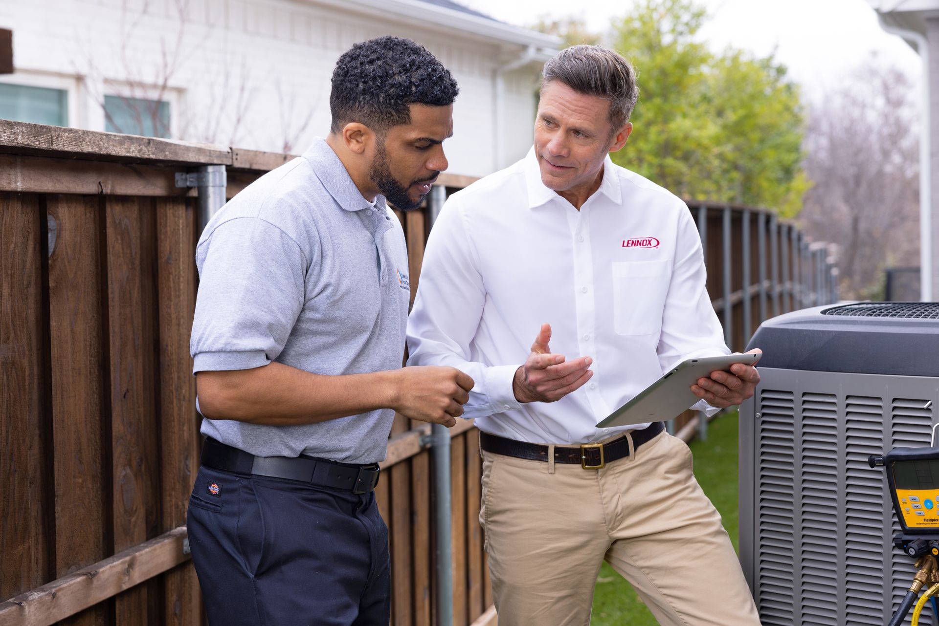 Two men are standing next to each other looking at a tablet.