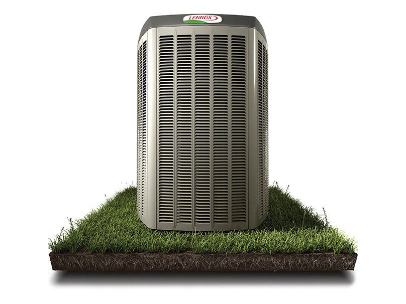 An air conditioner is sitting on top of a patch of grass.