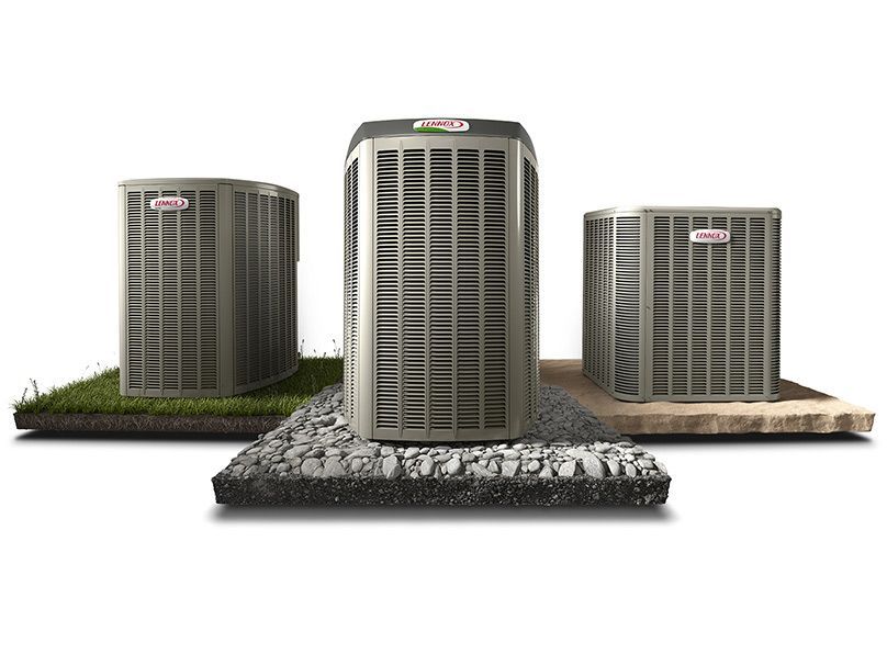 Three air conditioners are sitting on top of a pile of rocks.