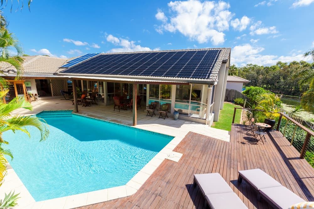 A House With A Swimming Pool And Solar Panels On The Roof — Mediterranean Custom Pools In Kialla, VIC