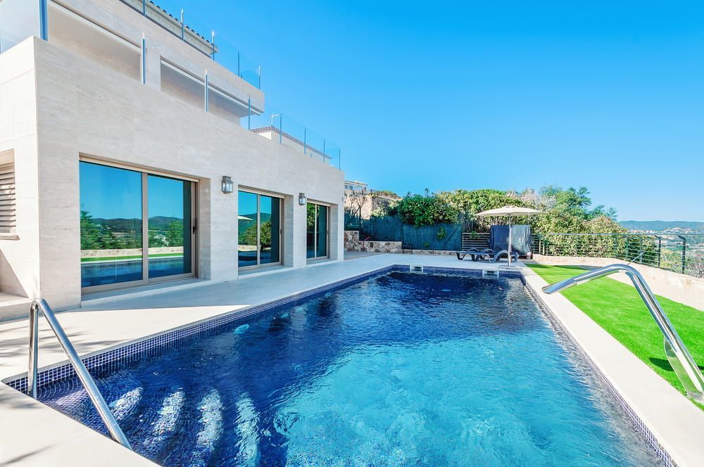 A Large White House With A Swimming Pool In Front Of It — Mediterranean Custom Pools In Kialla, VIC