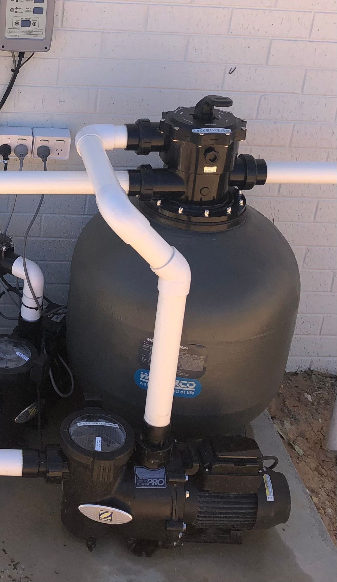 A pool pump on the ground nest to a brick wall — Mediterranean Custom Pools In Kialla, VIC