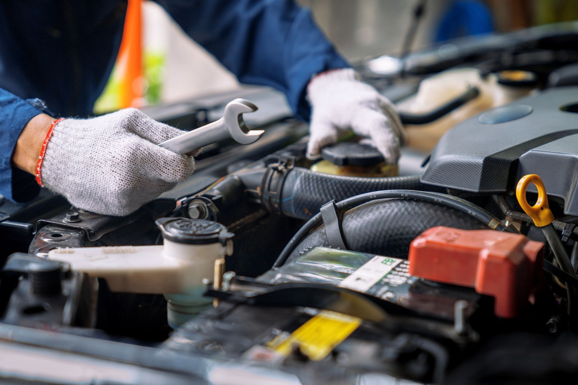 A mechanic is working on a car engine with a wrench.