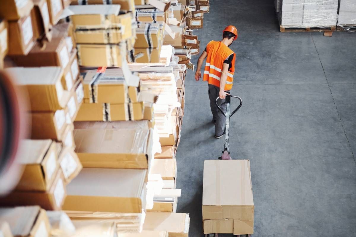 A distribution center employee pulling a crate on a cart near a large stack of crates at  C & S Transportation near Nicholasville, Kentucky (KY)