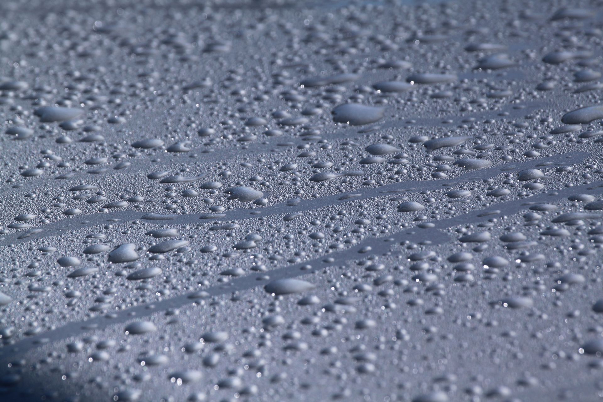 A close up of water drops on a gray surface. A close up of water drops on a gray surface.