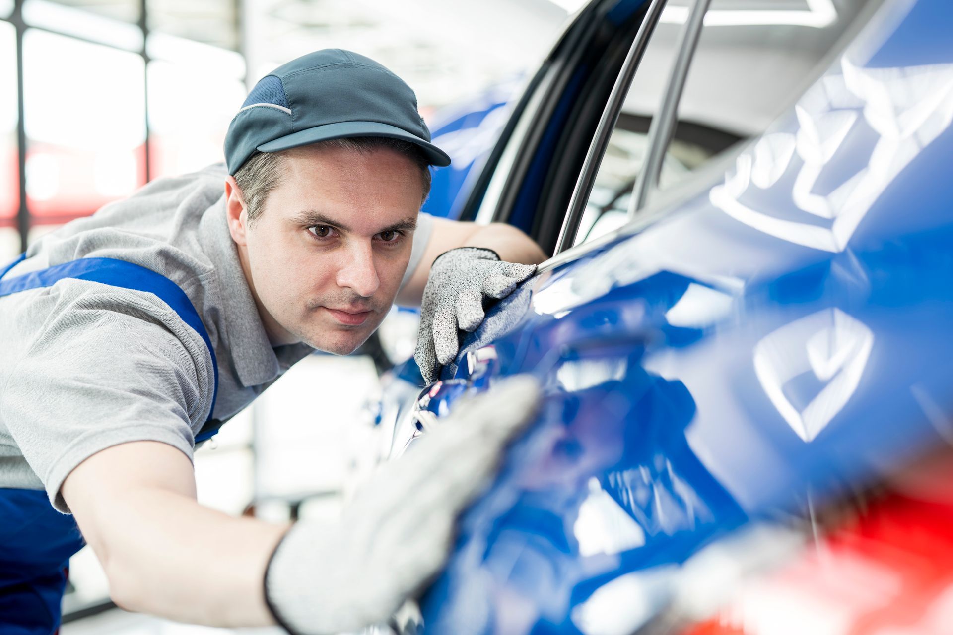 A man is working on a blue car in a garage