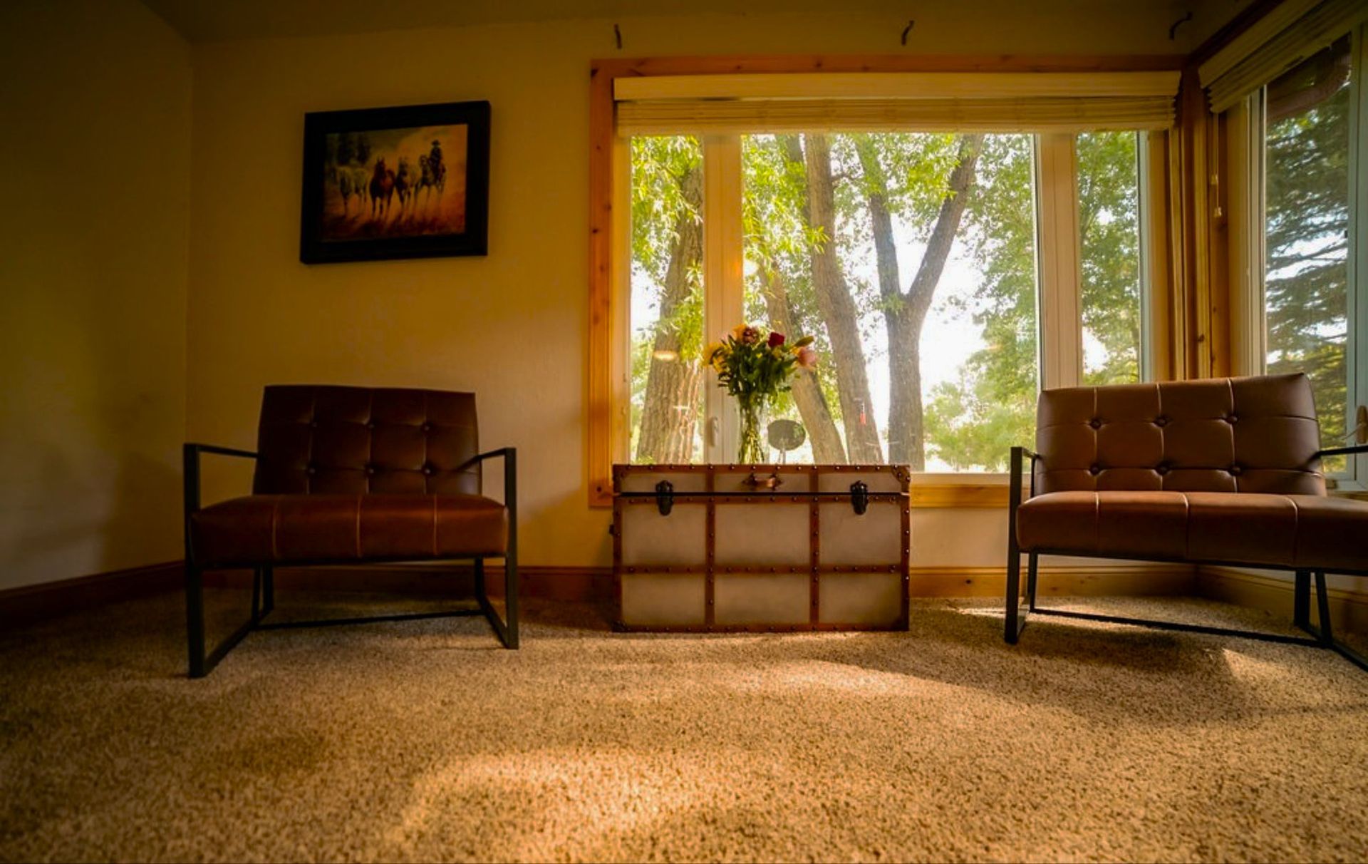 A living room with two chairs and a trunk in front of a window.