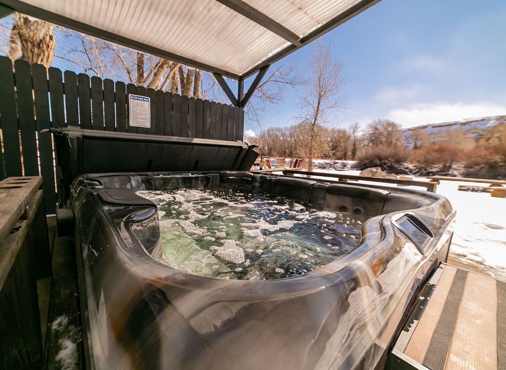 A hot tub is sitting under a roof in the snow.