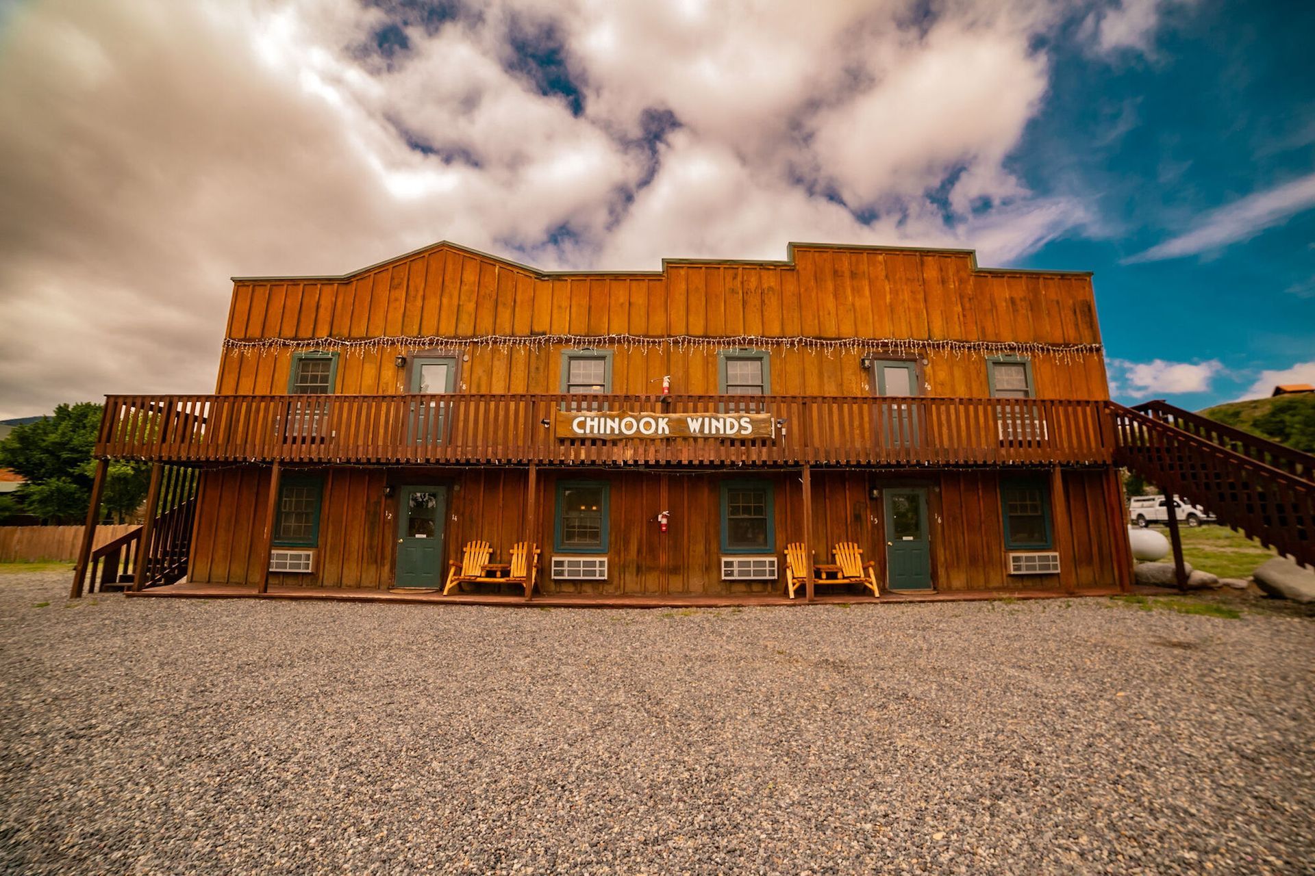 A large wooden building with stairs and chairs in front of it.