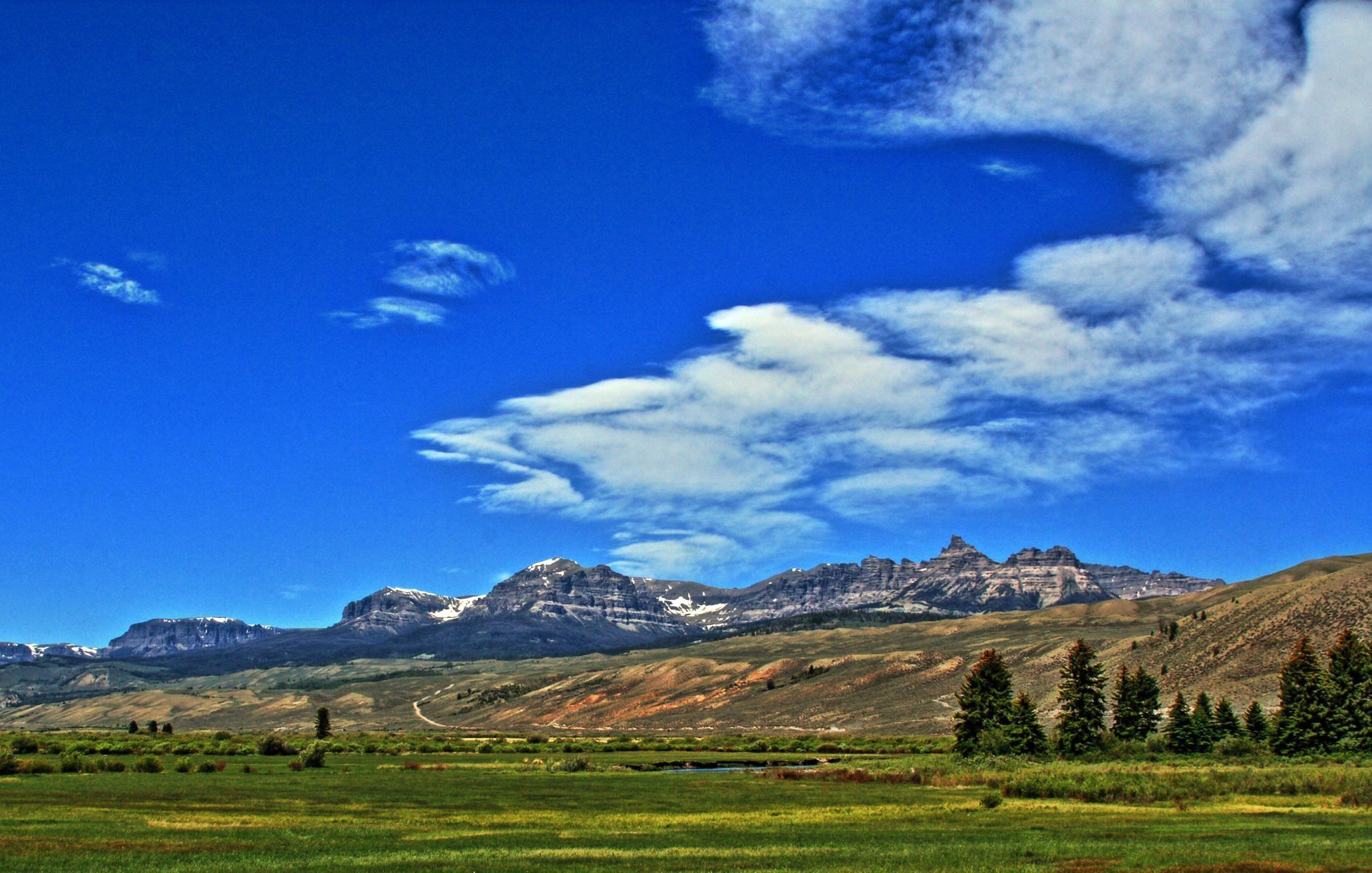 A field with mountains in the background and clouds in the sky