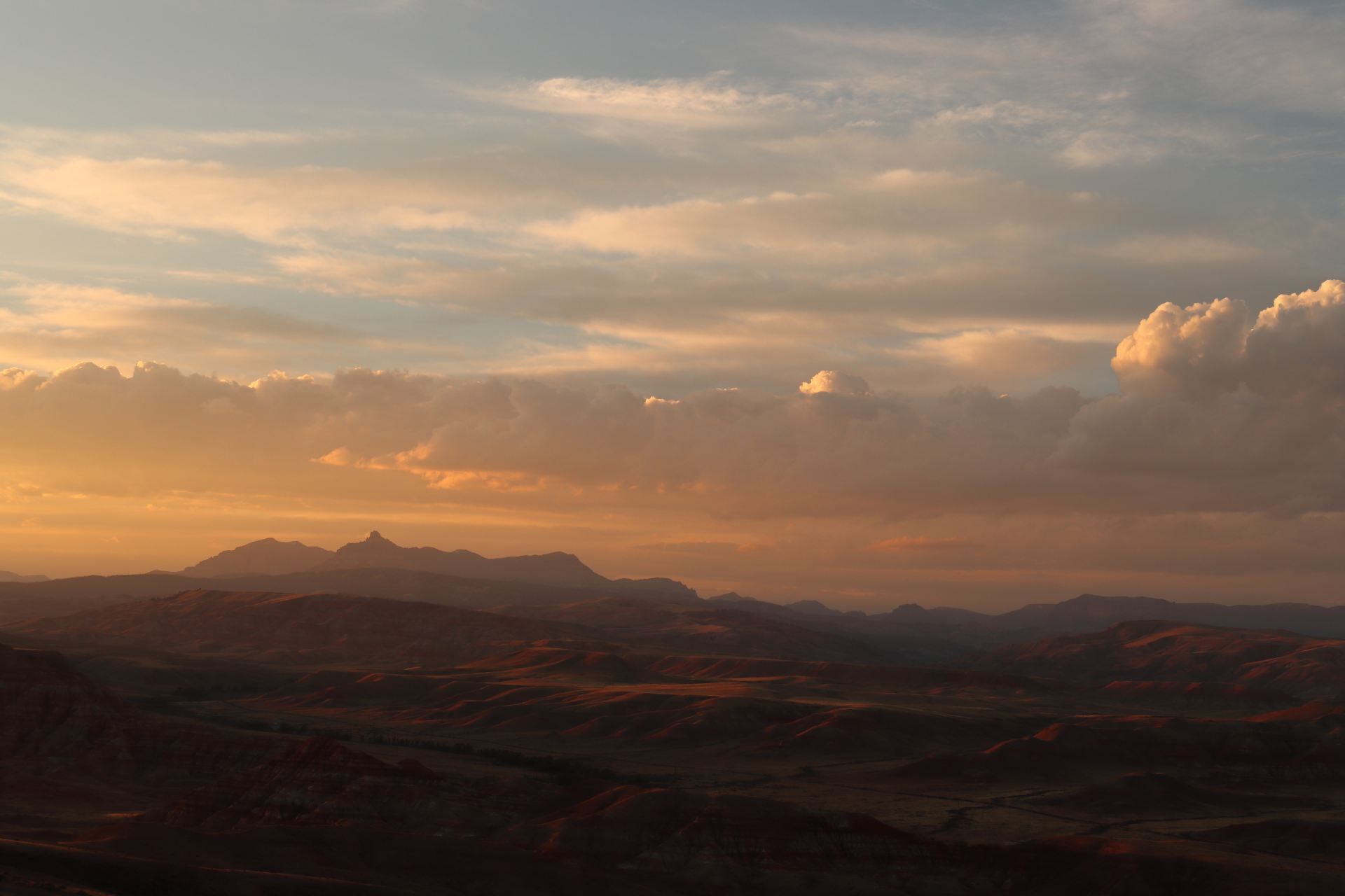 A sunset over a valley with mountains in the background