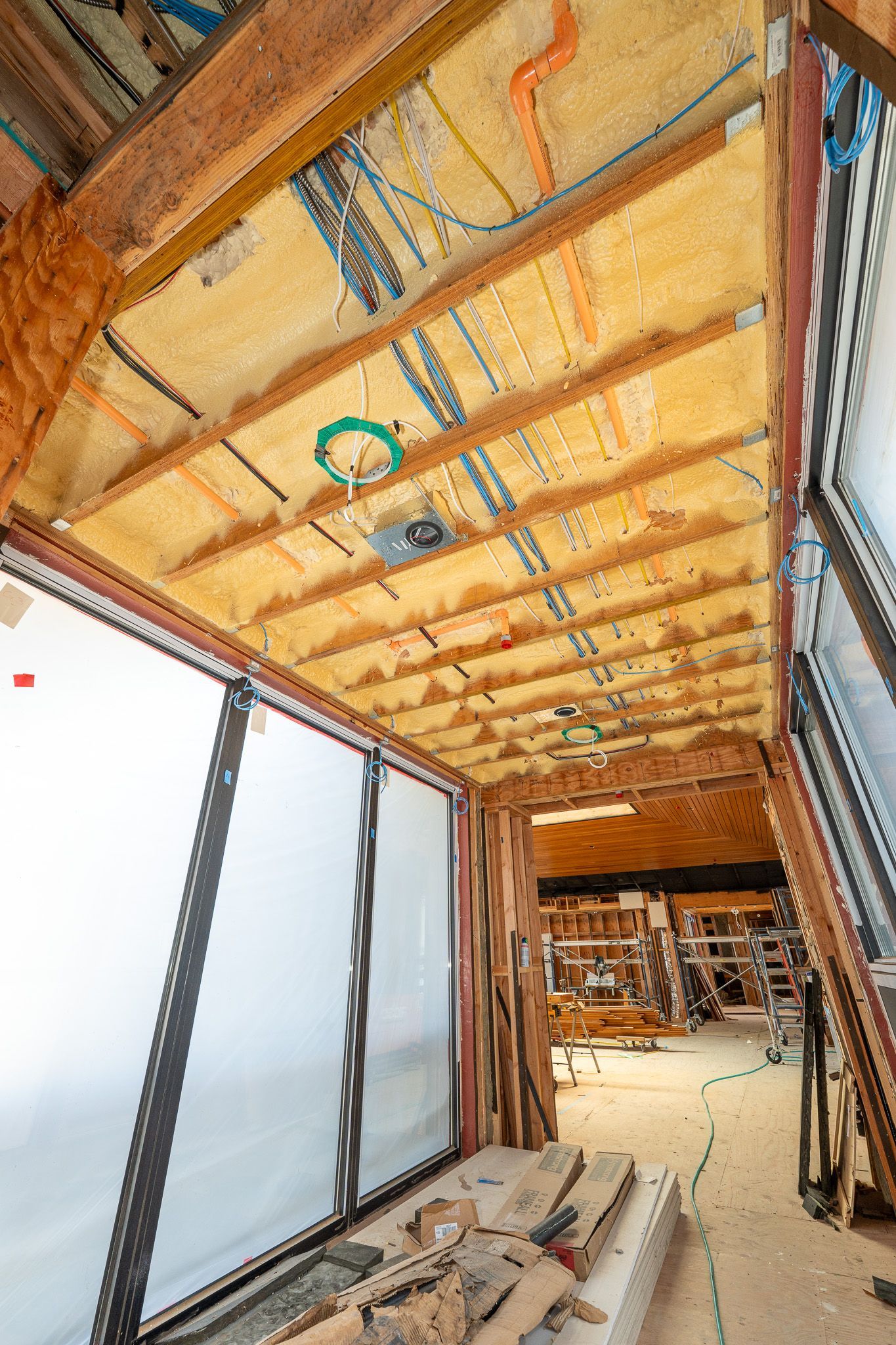 Unfinished room with exposed insulation, two windows, and bare walls under construction