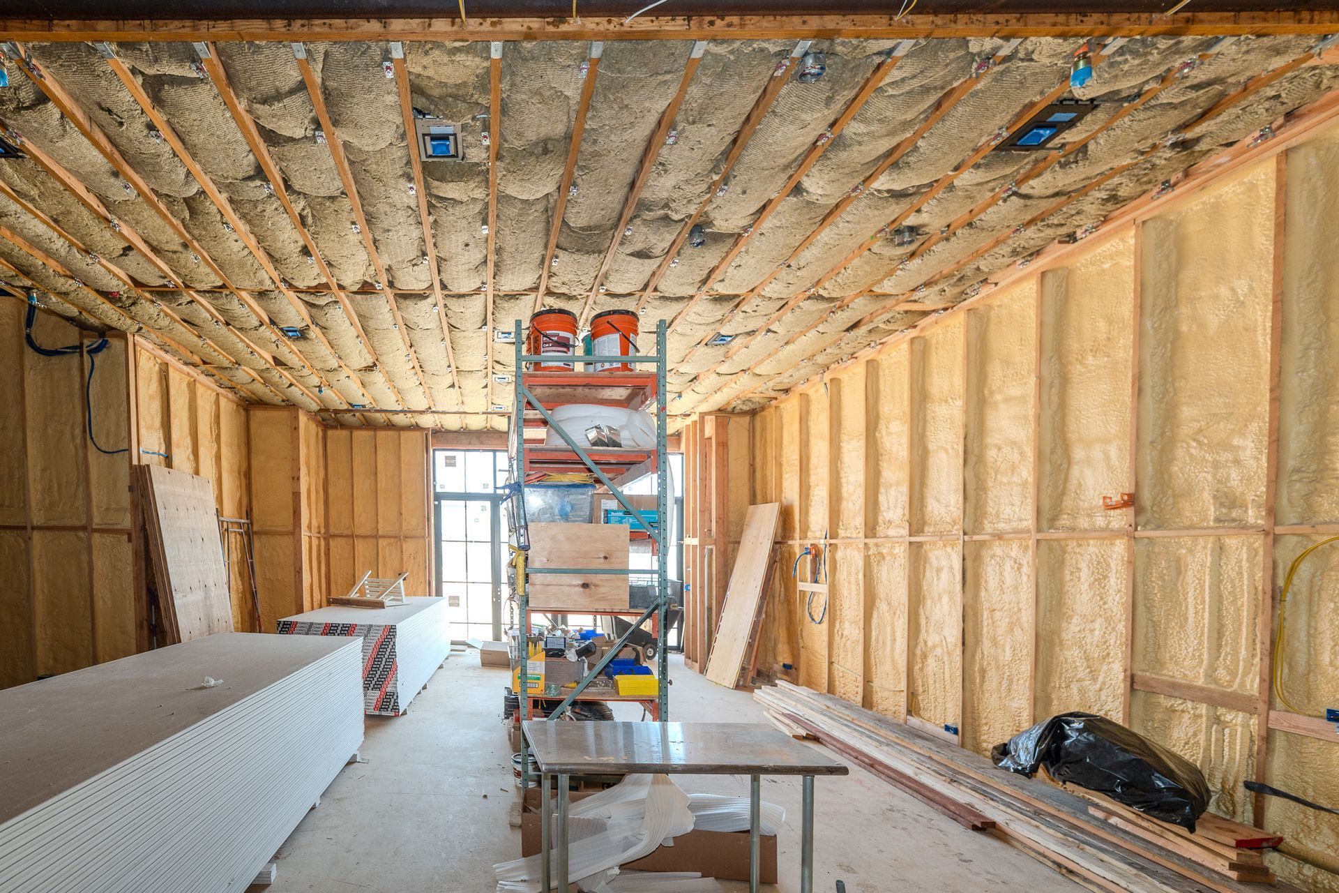 Unfinished room with exposed insulation, two windows, and bare walls under construction