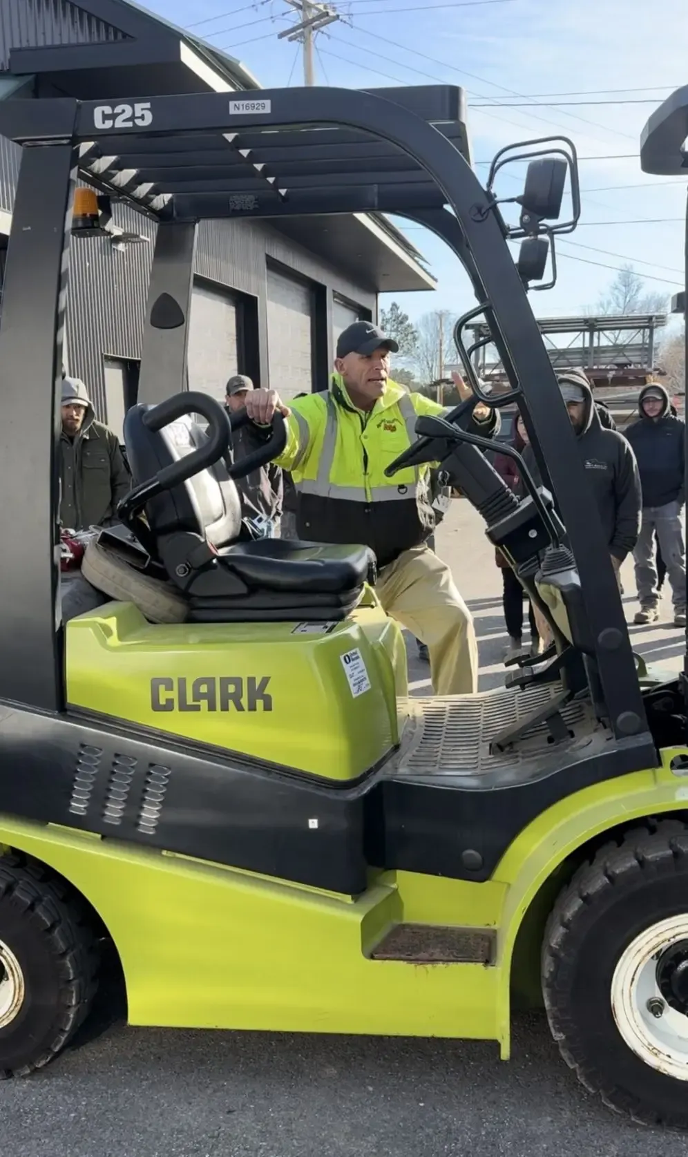 Paul Soracco of Motive Solutions LLC in a neon yellow high-vis jacket sits on a green and black forklift during a training.