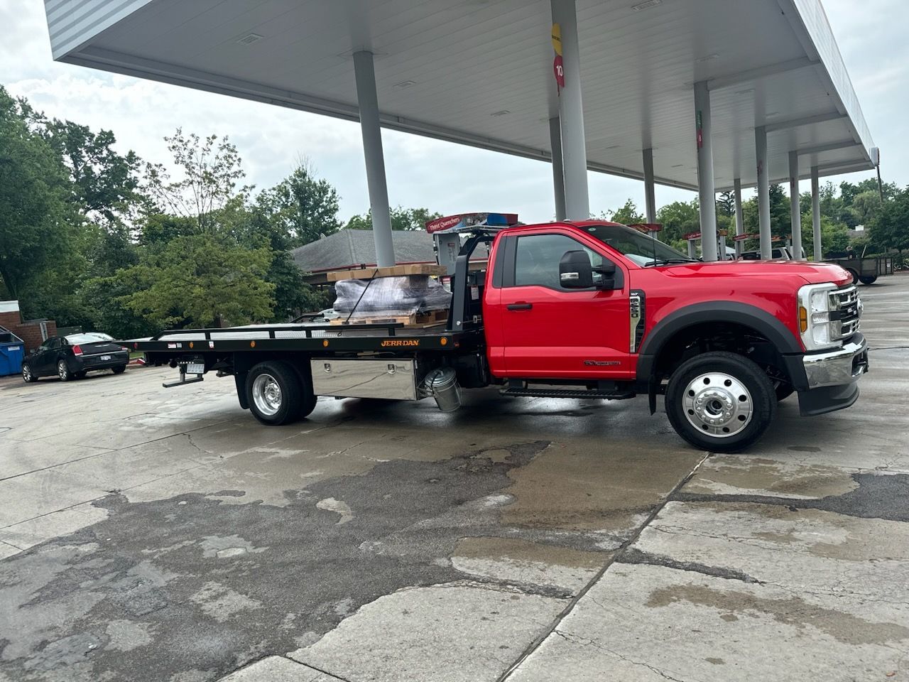 A red tow truck is parked in front of a gas station.