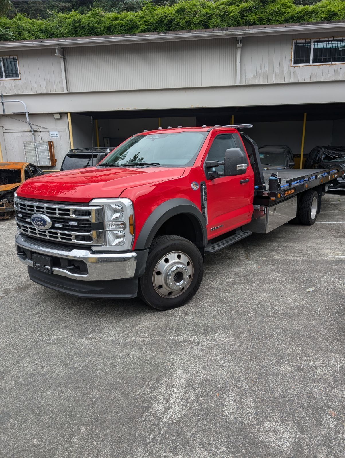 A red tow truck is parked in a parking lot in front of a building.