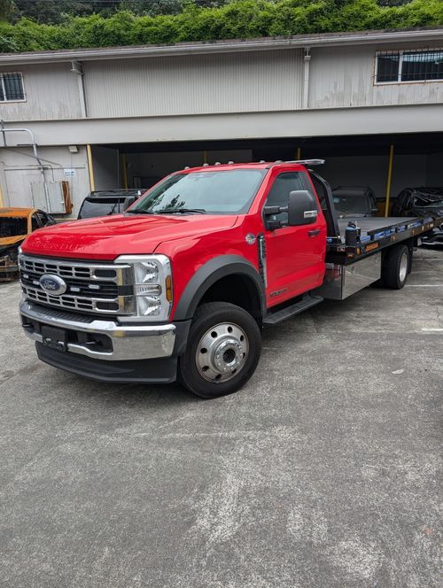 A white truck is being towed by a tow truck.