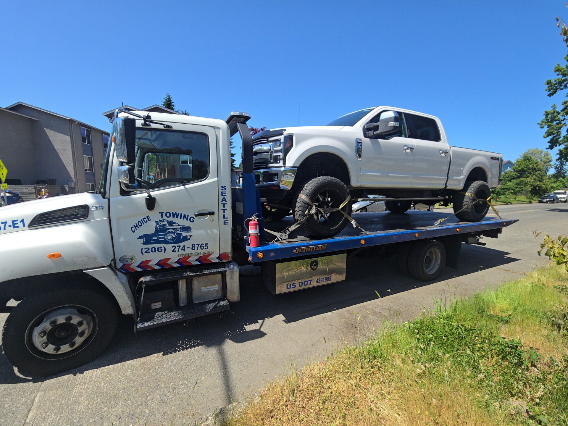 A white truck is being towed by a tow truck.