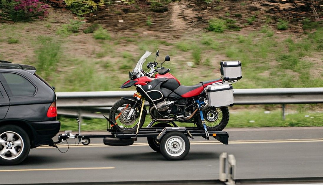 A motorcycle is being towed by a car on a trailer.