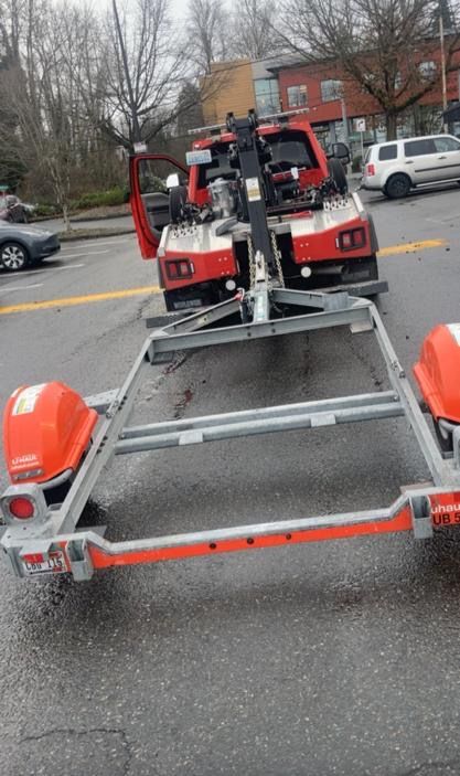 A tow truck is towing a car on a trailer.