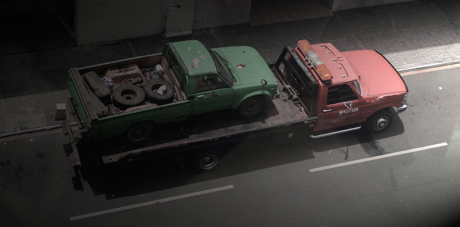 A green pickup truck is being towed by a red tow truck on a dark road.