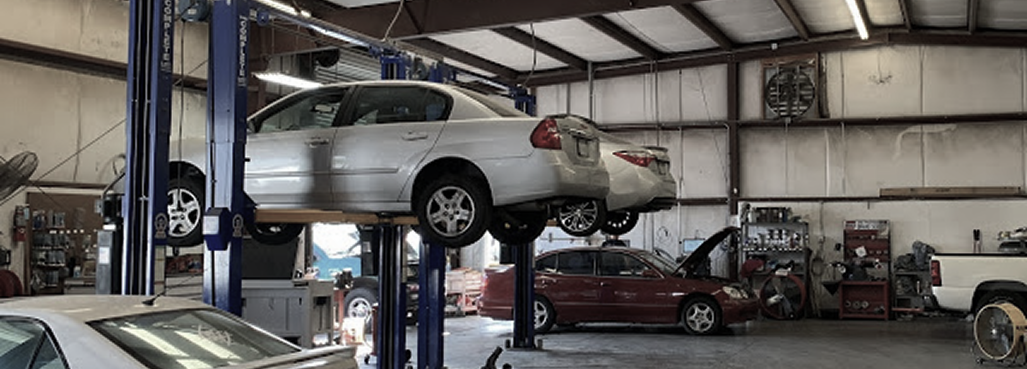 Cars being serviced on lifts inside an auto repair shop.