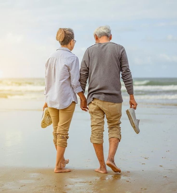 a man and woman walking on the beach holding hands