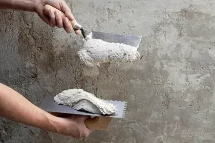 A person is plastering a wall with a trowel.