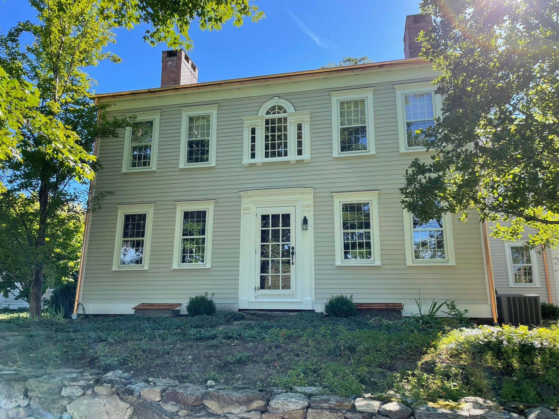 A large house with a lot of windows is sitting on top of a hill.