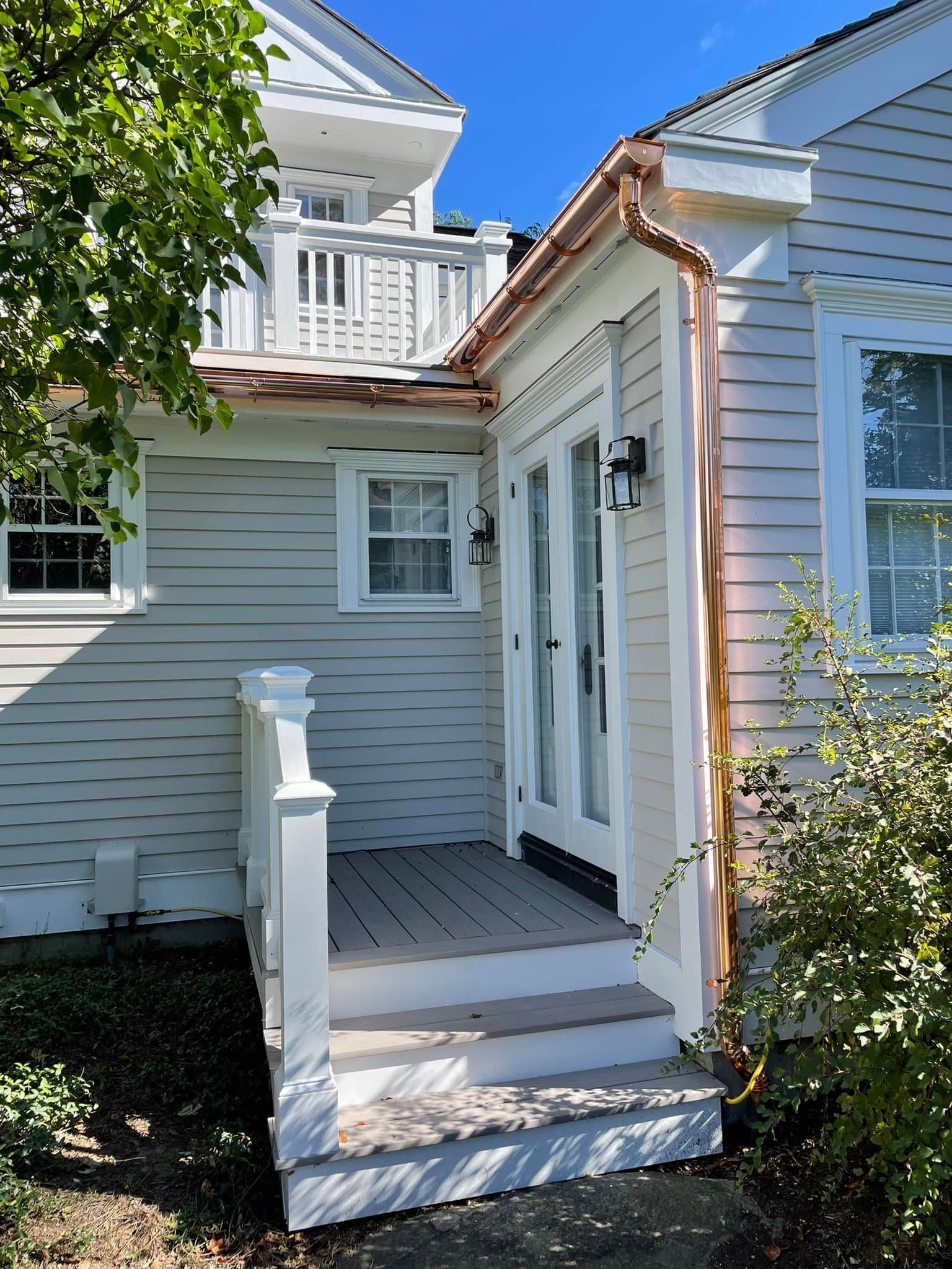 A white house with a copper gutter on the side of it
