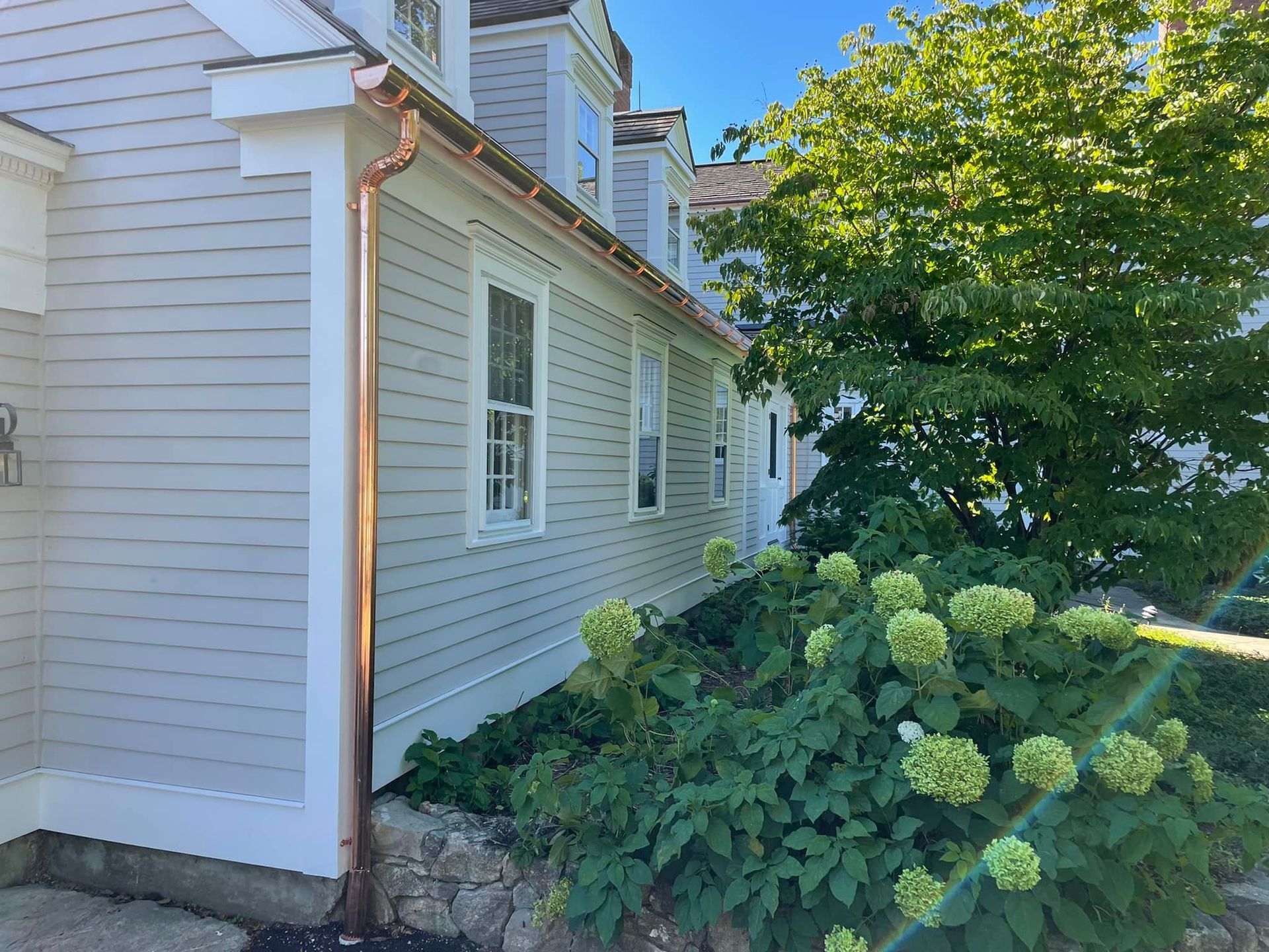A white house with a copper gutter on the side of it.
