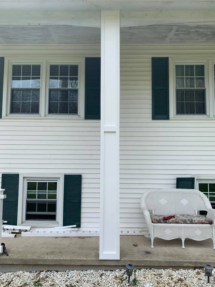 A white house with green shutters and a white couch on the porch