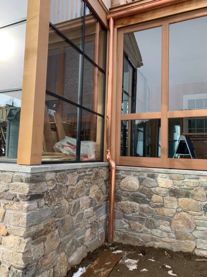 A house with a stone wall and copper gutters
