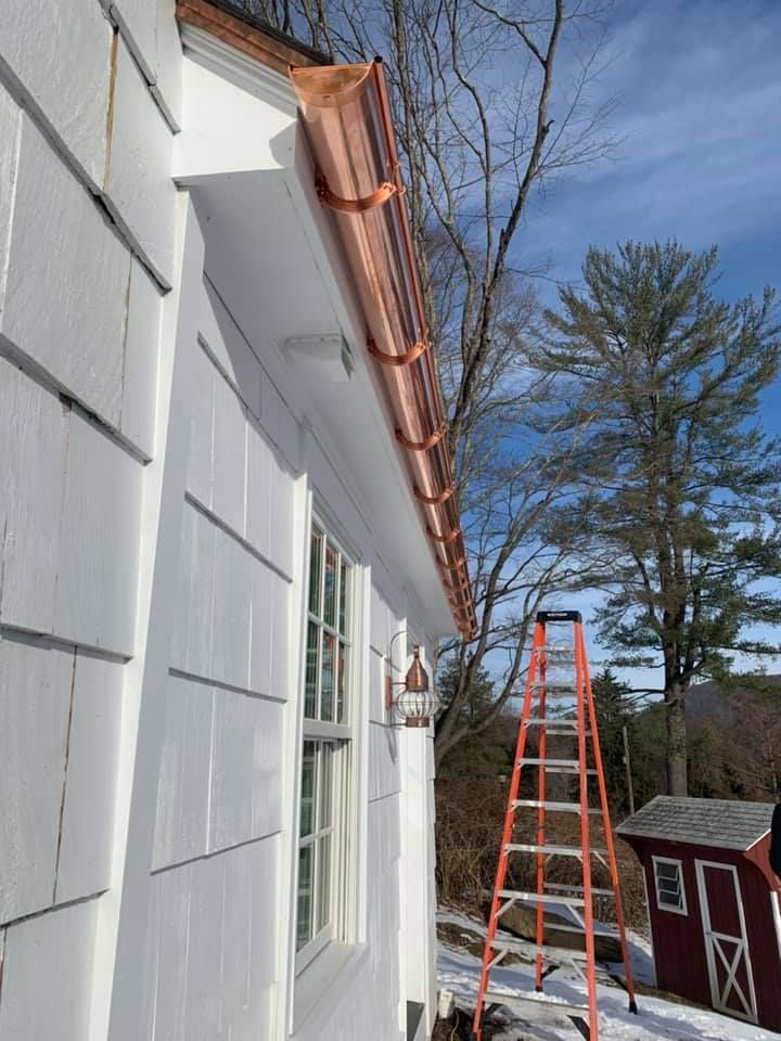 A copper gutter is being installed on the side of a house.