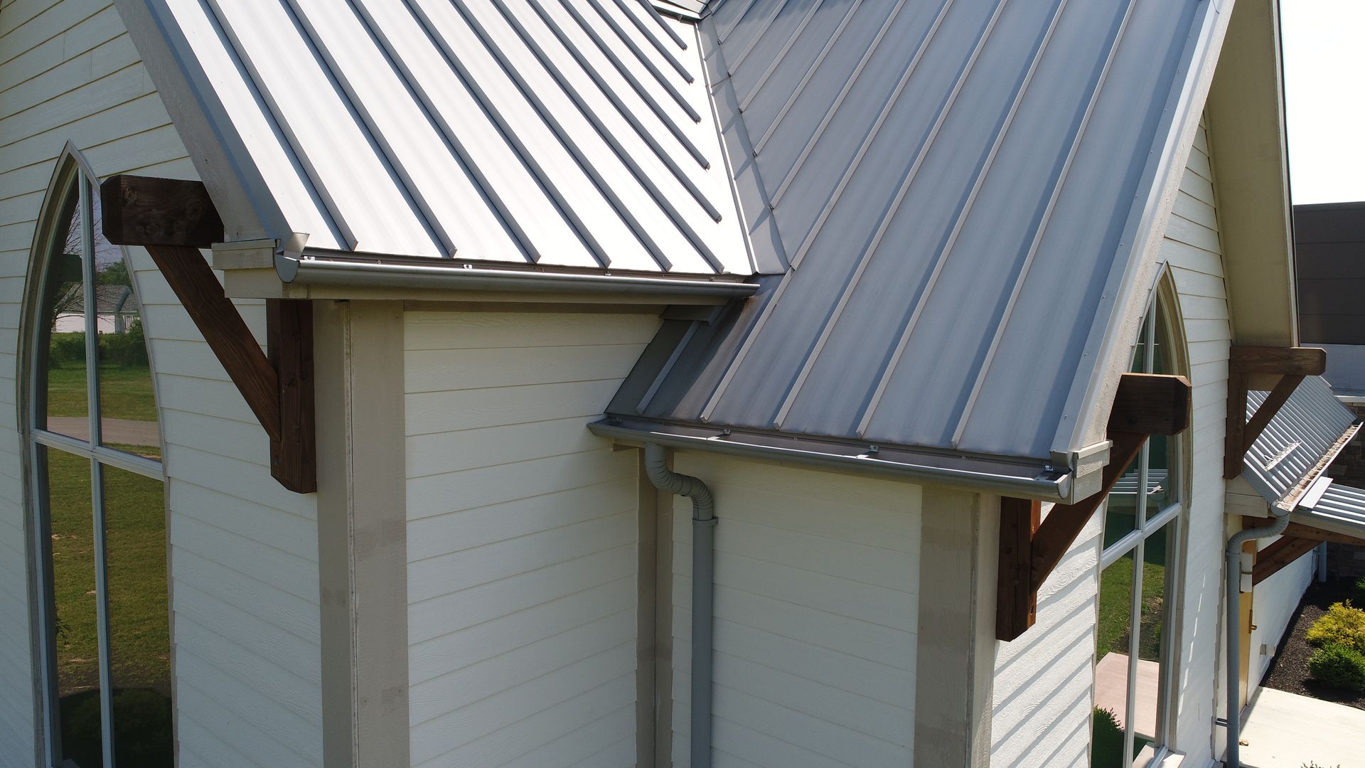 A white house with a metal roof and gutters