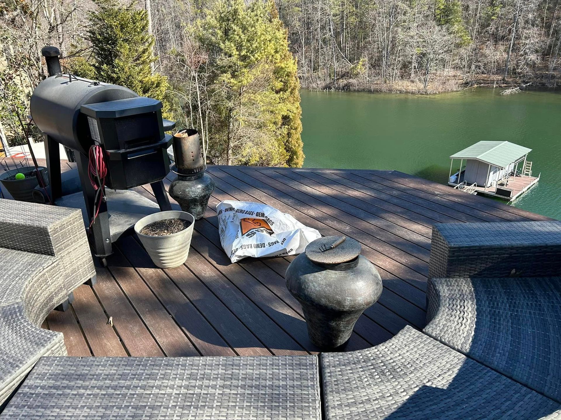 A wooden deck with a grill and a boat in the background.