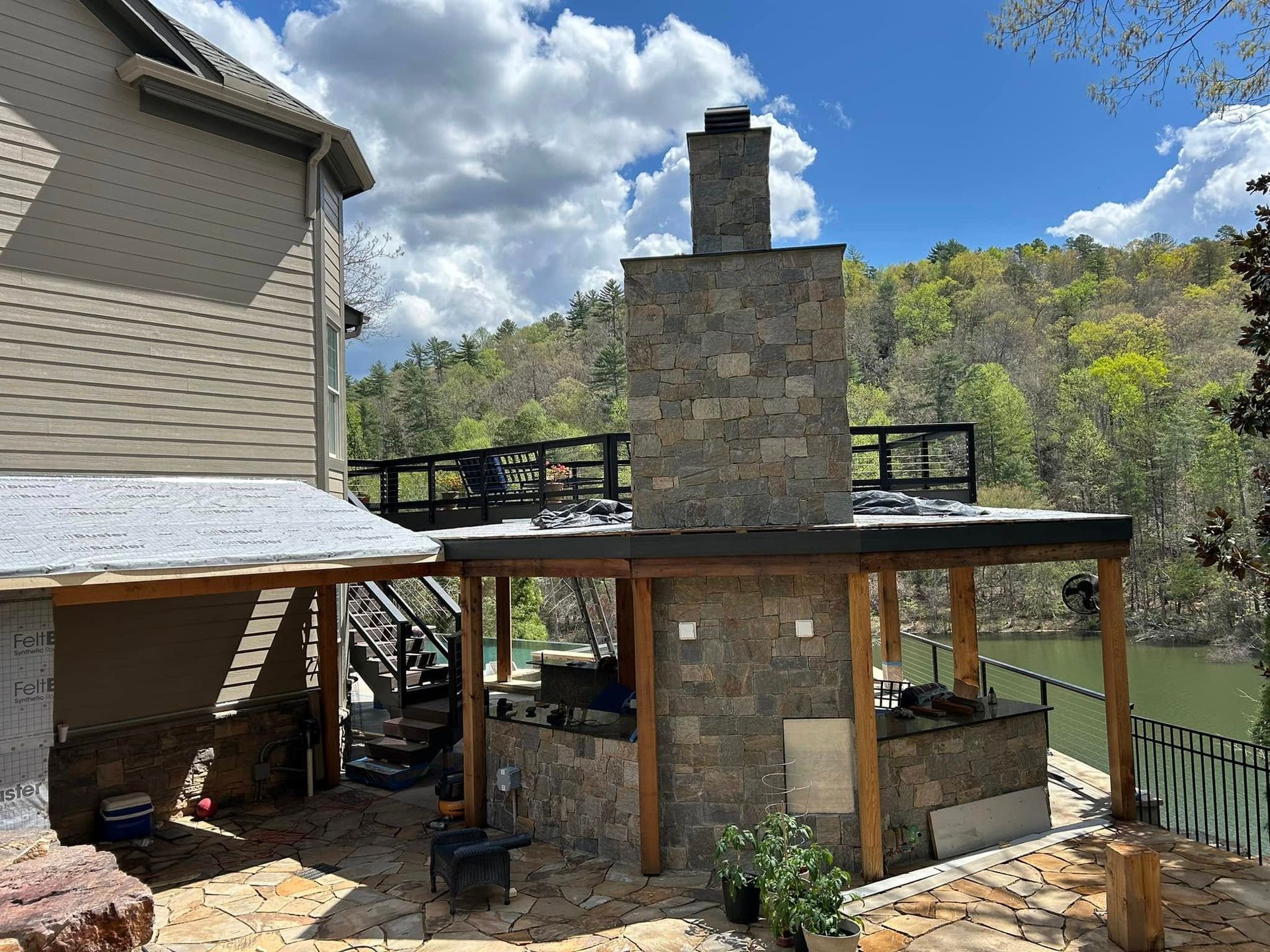 A house with a fireplace and a deck overlooking a lake.