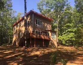 A large house is sitting on top of a hill in the middle of a forest.