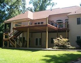 A large house with a wooden deck and stairs.