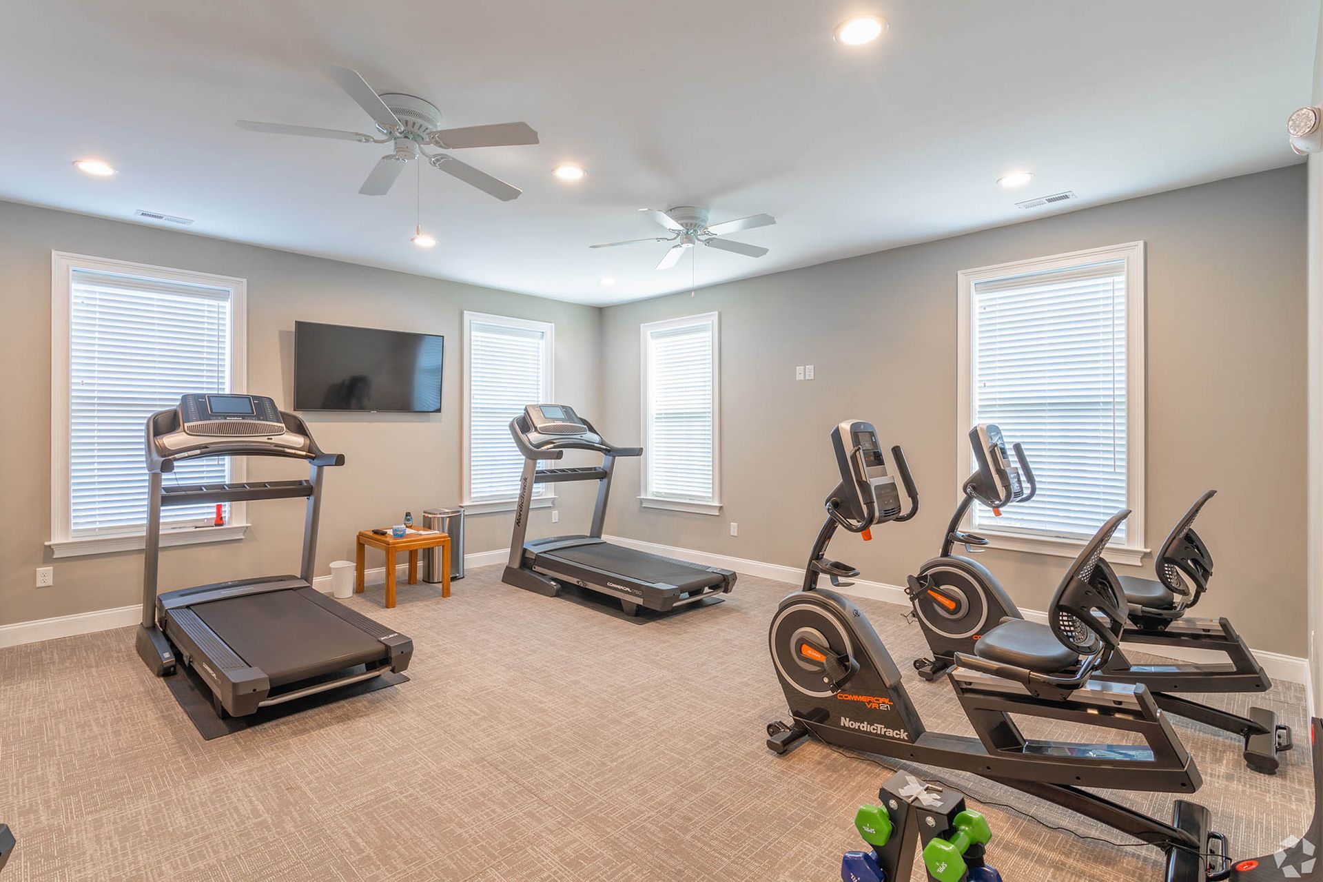Bright community gym with treadmills, stationary bikes, ellipticals, and free weights at The Residences at St. Joseph's Court in Levittown, PA.