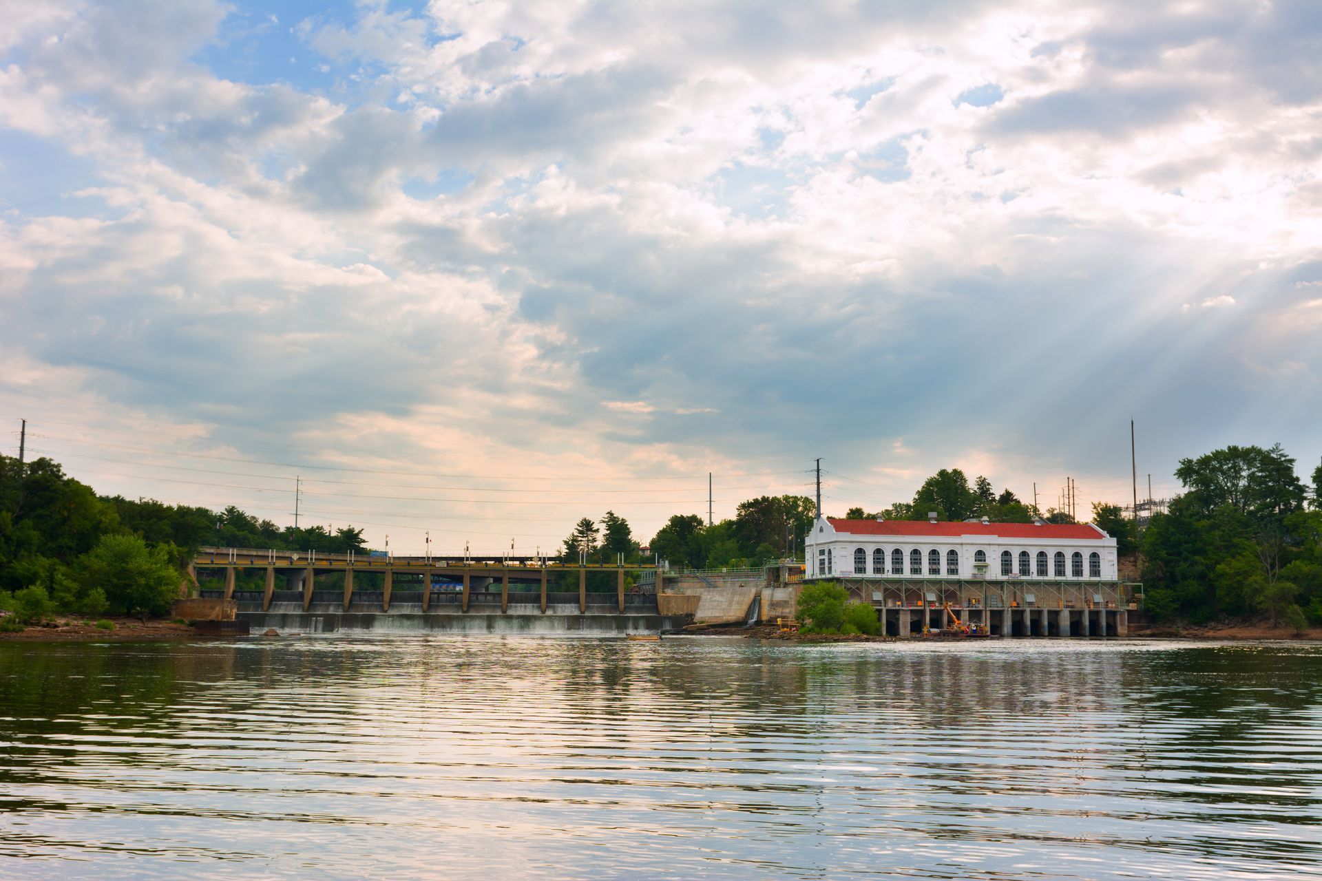 A white building with a red roof is sitting on the shore of a lake.