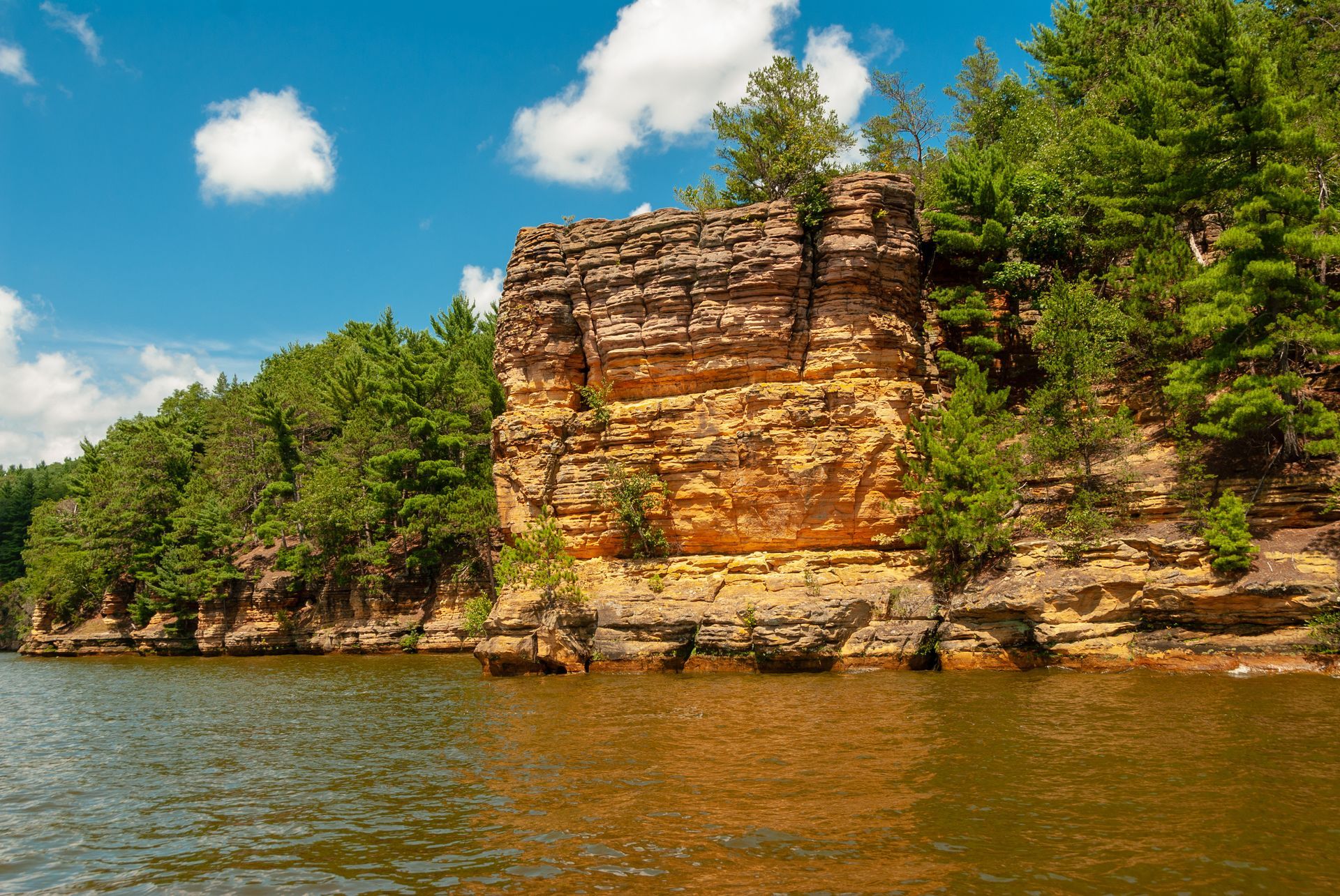 There is a large rock formation in the middle of a lake surrounded by trees.