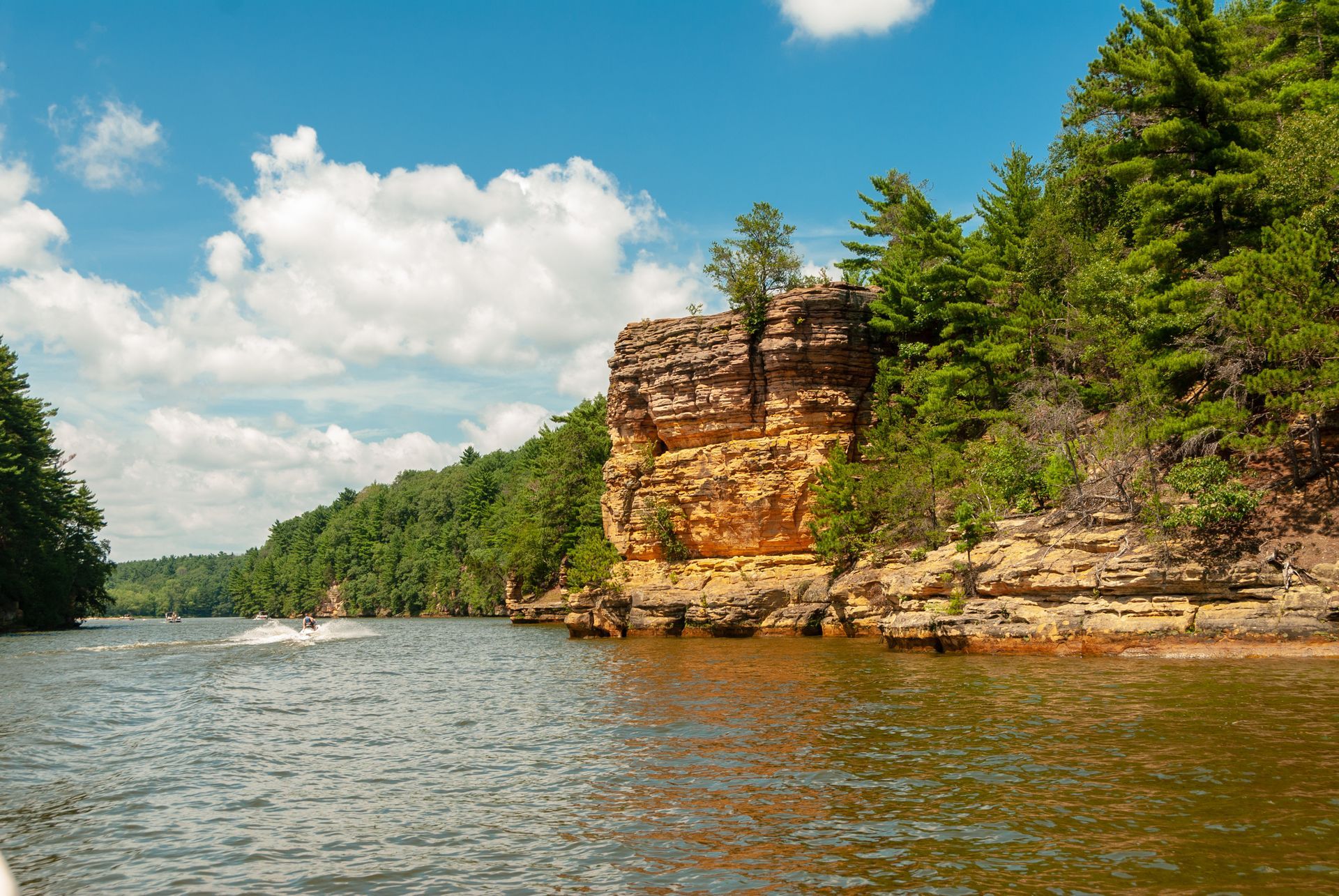 A boat is floating on a lake near a rocky cliff.
