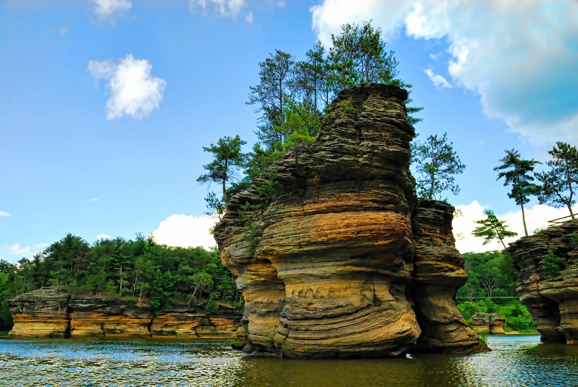 A large rock in the middle of a lake with trees on it