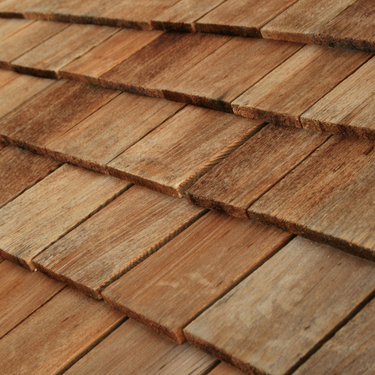 Close-up of overlapping wooden shingles, showing the texture and natural wood tones.