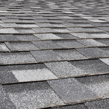 Gray asphalt shingle roof. Close-up view of overlapping textured rectangular tiles.