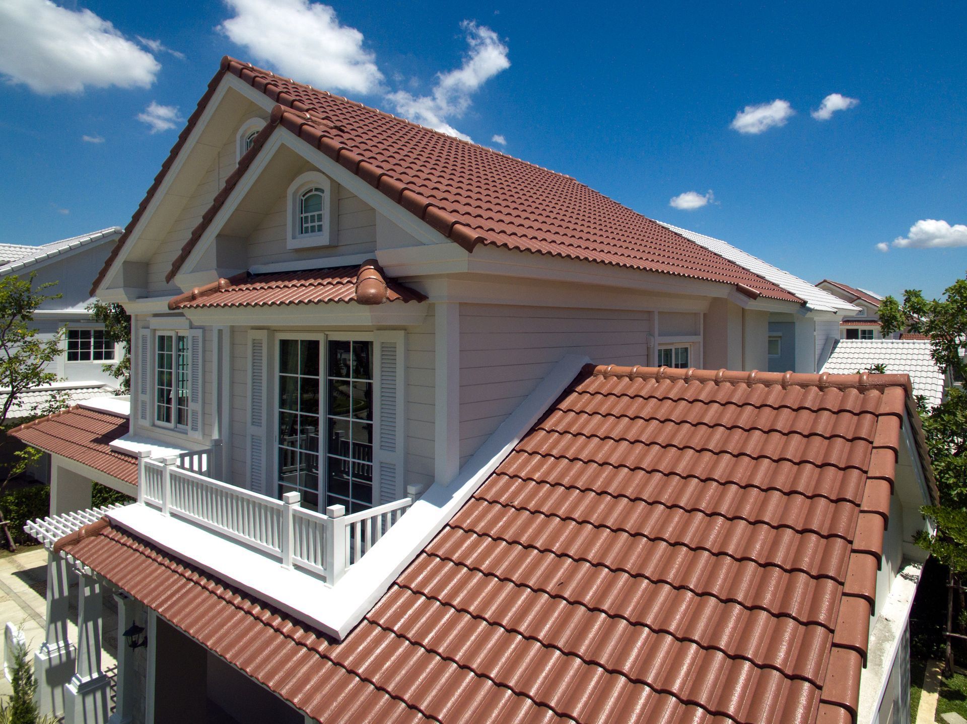 House with red tile roof and white exterior on a sunny day.